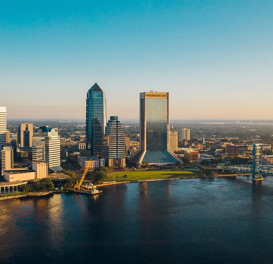 Aerial view of a city skyline with tall buildings and a river in the foreground during daytime.
