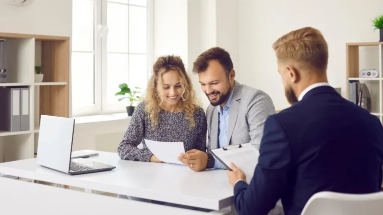 Three professionals, two men and one woman, reviewing documents in a bright office setting.