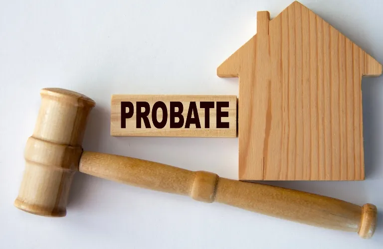 Wooden gavel beside a wooden house model and a block with the word "PROBATE" in black letters.
